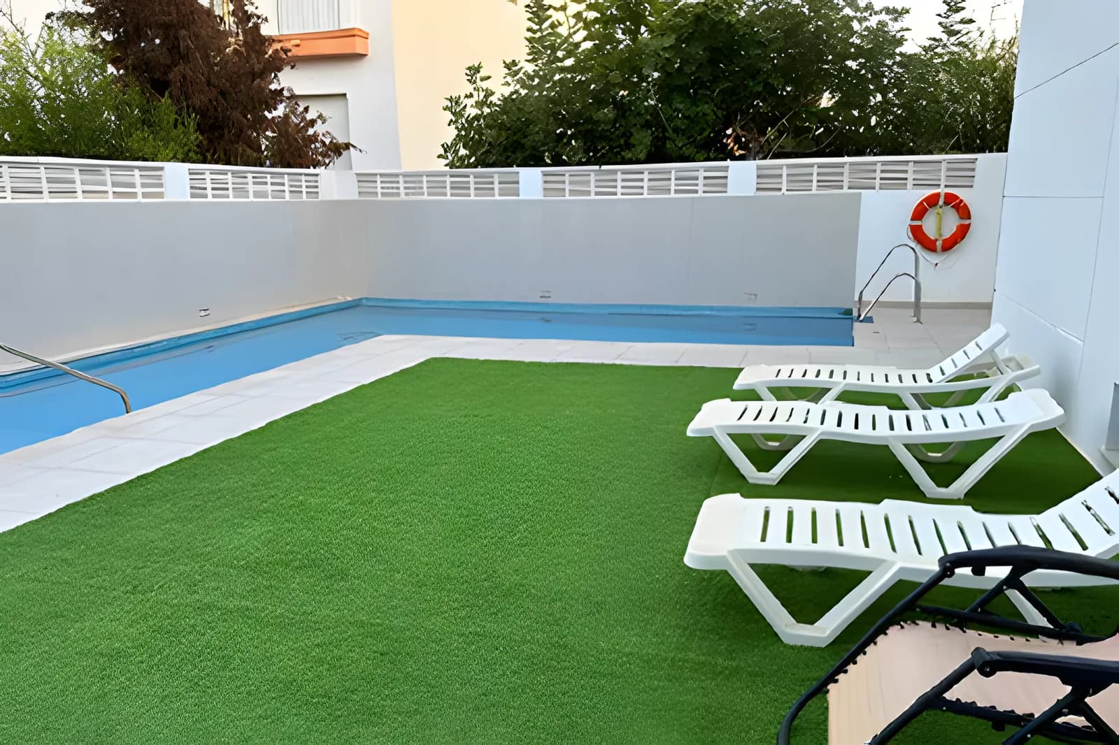 Piscina del hostal con tumbonas y césped